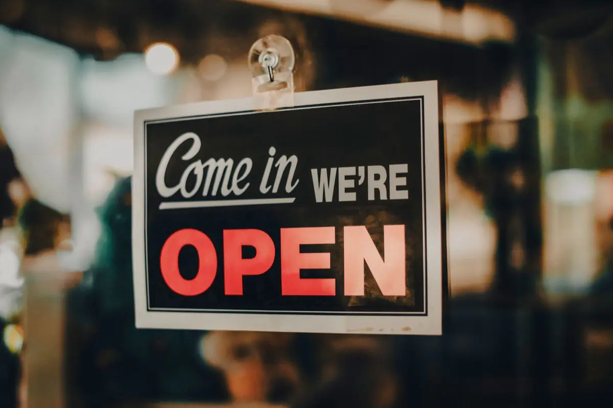A come in we are open sign hanging in a shop window