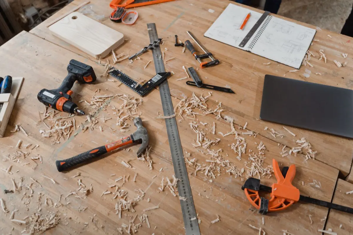 Carpentry tools and sketches on a workbench covered in wood shavings