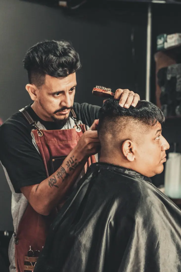 A barber cutting a customer's hair in a shop